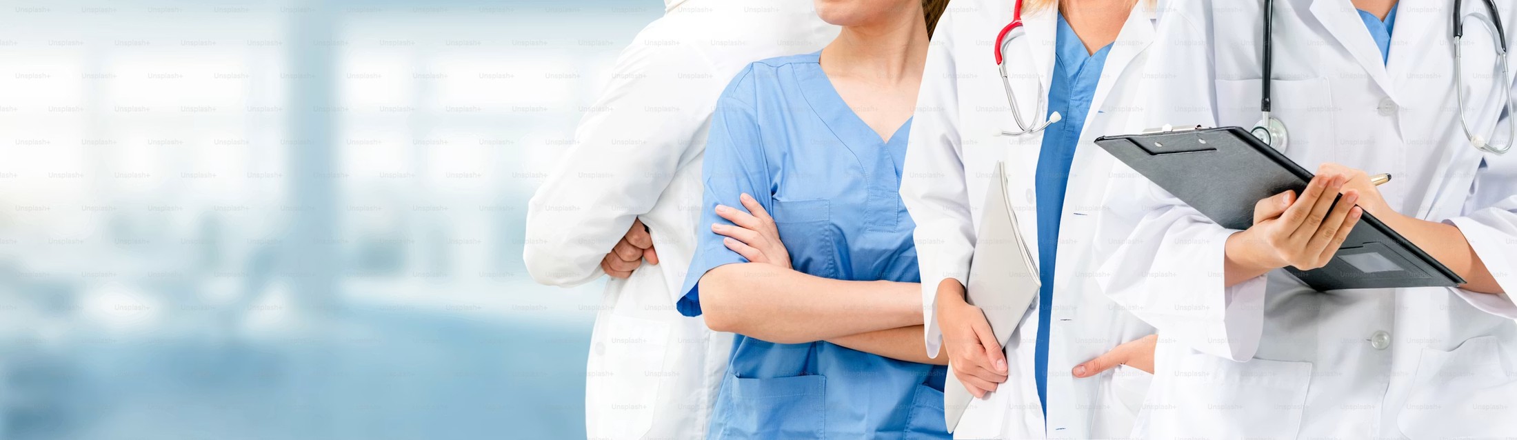 Equipo médico de la clínica de pie con batas y estetoscopios